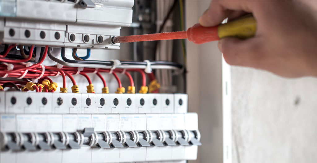 Gros plan sur des disjoncteurs modulaires alignés dans un tableau électrique moderne, avec un léger flou d'arrière-plan